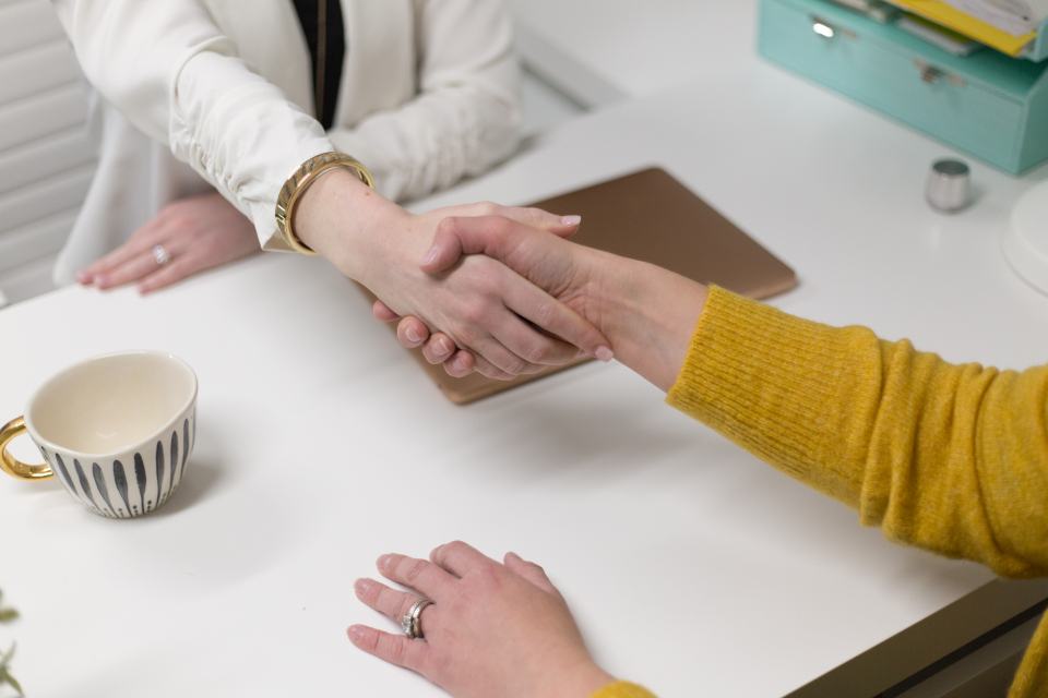 Deux personnes se serrent la main au-dessus d'un bureau