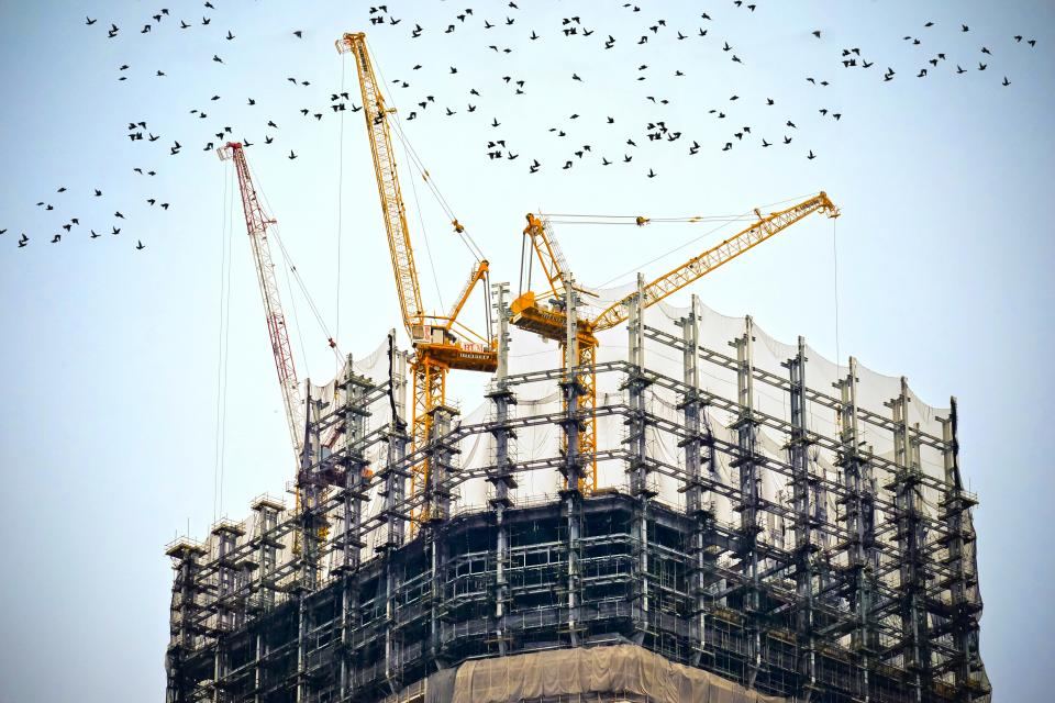 Un immeuble en construction entouré de grues