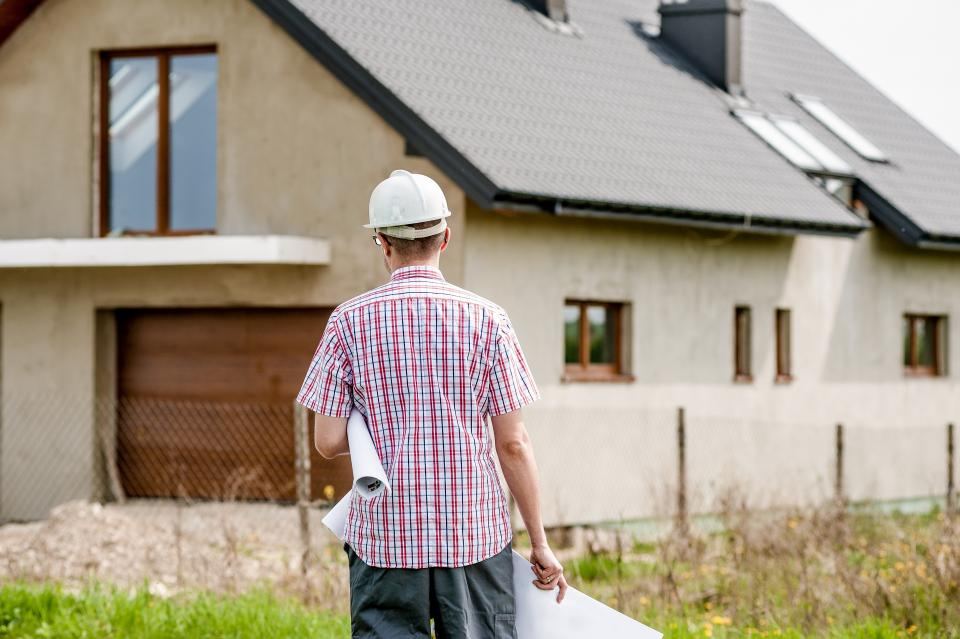 Un conducteur de travaux, plans en main, devant une maison en chantier
